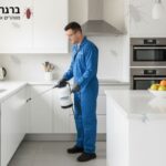 טכנאי הדברה מקצועי שלובש חליפת מגן כחולה בסגנון סוודר, מרסס נגד ג'וקים.